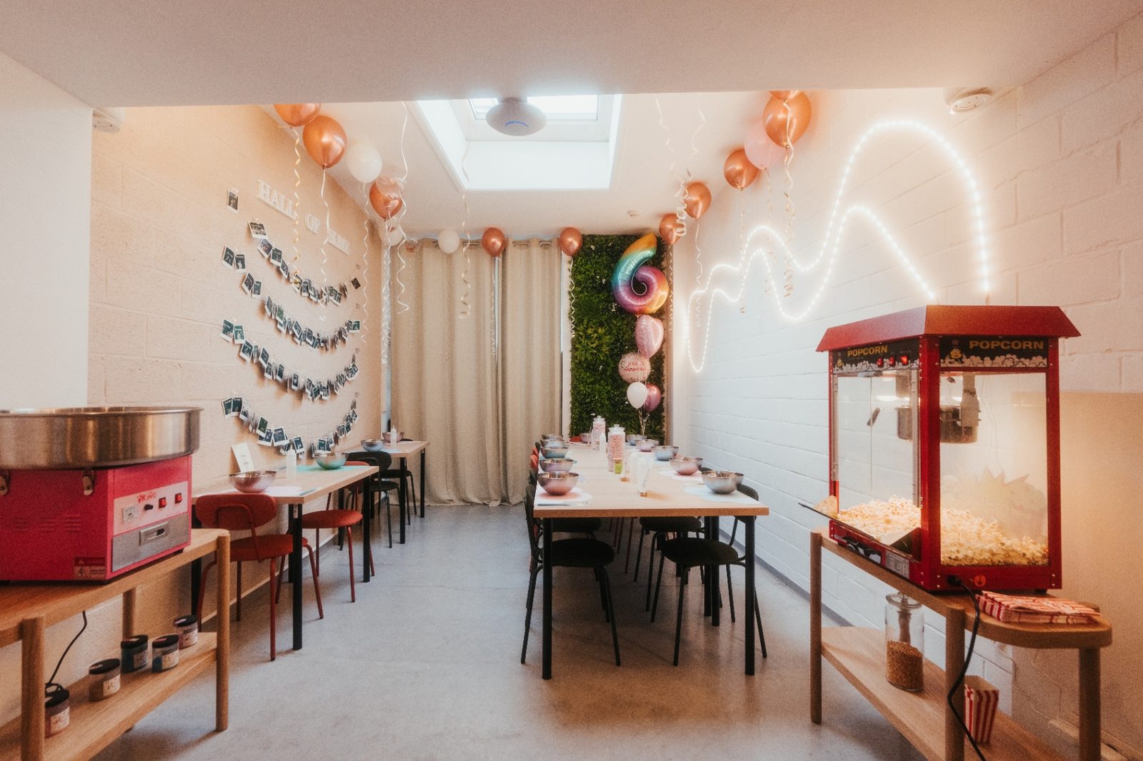 Atelier slime à Mons — salle décorée avec ballons roses, guirlandes lumineuses, machine à barbe à papa et pop-corn pour anniversaire